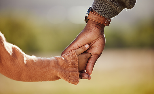 An adult holding the hand of a child