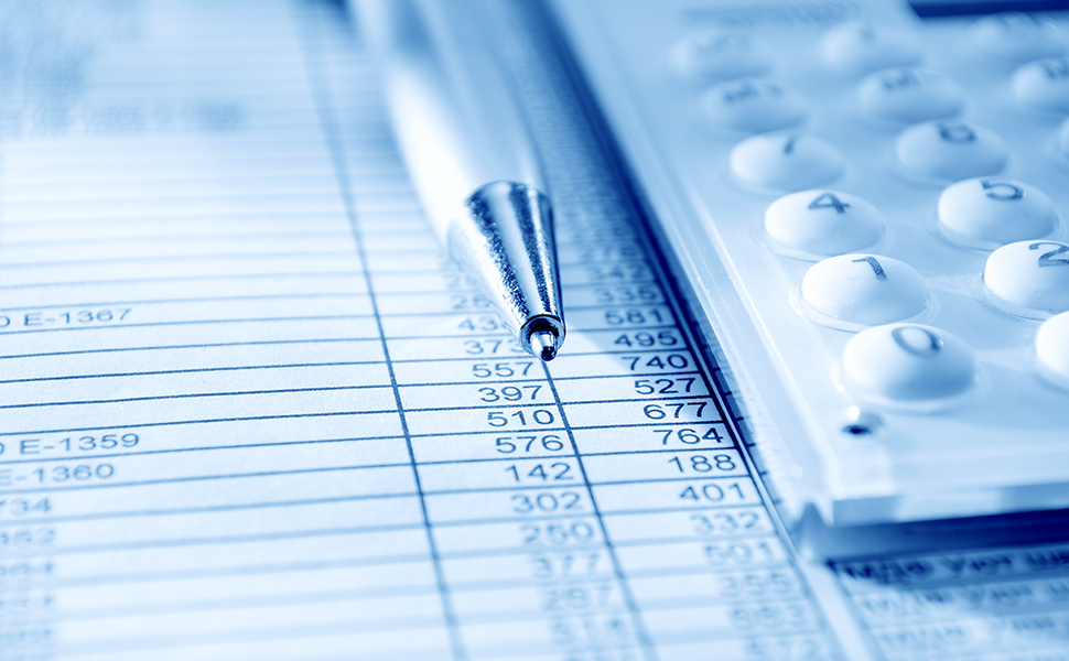 An image of a calculator and a pen atop a balance sheet